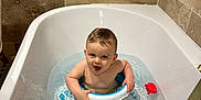 Paul a rejoint le concours — aidez-le/la à gagner de superbes lots ! baby, bathtub, bath_toys, water, splashing, float_ring, angelcare, tiled_wall, bathroom, child, smiling, playing, toy_crab, toy_fish, toy_whale, toy_turtle, toy_penguin, happy, sitting, infant