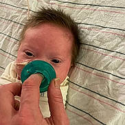 Bayne is registered to the contest to win money with this photo: baby, bed, care, closeup, comfort, eyes, face, feeding_tube, hair, hand, health, human, infant, lying_down, newborn, pacifier, person, rest, skin, striped_blanket
