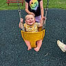 baby, child, swing, playground, grass, bench, smiling, happy, yellow_swing, black_shirt, person, footwear, outdoor, summer, fun, park, chain, seat, play, toddler