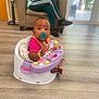 Liberty joined the competition — help win amazing prizes! baby, pacifier, toy, baby_seat, floor, adult, chair, window, natural_light, bracelet, bibs, person, indoor, wooden_floor, casual_clothing, sneakers, table, curious, seated, home