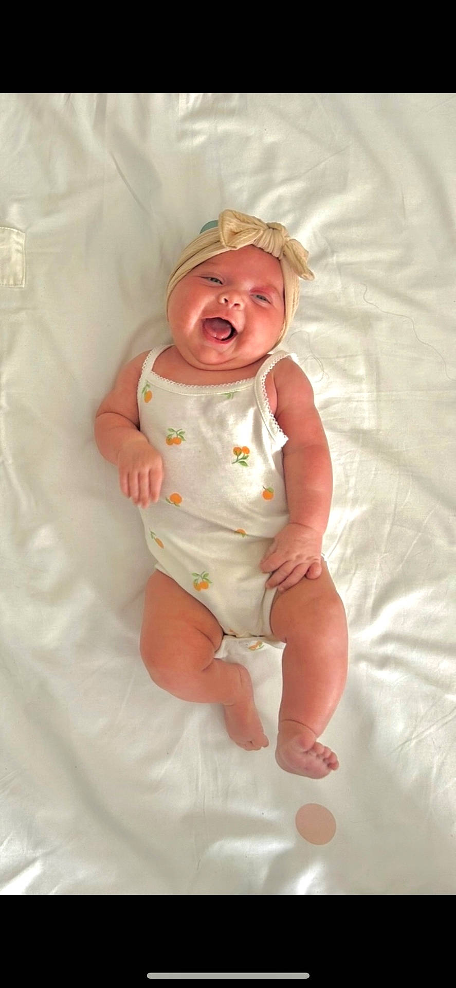 adorable, baby, blanket, bow, child, chubby, cute, happy, headband, infant, lying_down, onesie, orange_prints, peaceful, portrait, skin, smiling, soft, tongue_out, white
