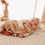 Emma participe au concours pour gagner de l'argent avec cette photo : baby, smiling, infant, blanket, headband, beige_clothing, cozy, lying_down, happy, indoors, decor, vase, dried_flowers, soft_lighting, portrait, cute, warm_colors, child, fabric, closeup