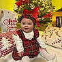 baby, child, christmas_tree, holiday, festive_clothing, beret, red_plaid, smiling, decorations, ornaments, lights, pillow, cushion, home_interior, celebration, cute, happy, sitting, white_socks, seasonal