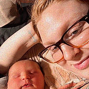 Isabella is registered to the contest to win money with this photo: newborn, baby, person, glasses, sleeping, cuddle, blanket, indoor, portrait, closeup, skin, face, hand, cozy, warm_light, wooden_background, resting, family, love, comfort