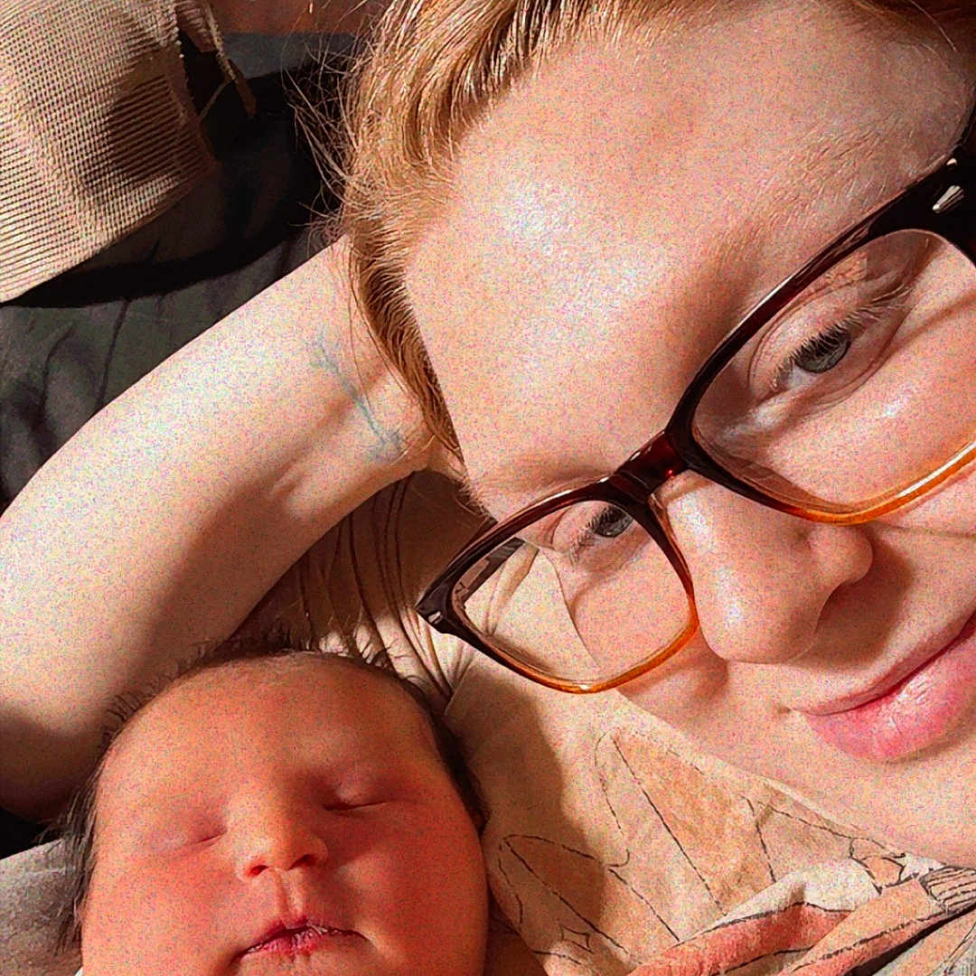 Isabella is registered to the contest to win money with this photo: newborn, baby, person, glasses, sleeping, cuddle, blanket, indoor, portrait, closeup, skin, face, hand, cozy, warm_light, wooden_background, resting, family, love, comfort