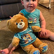 Adelio joined the competition — help win amazing prizes! toddler, child, teddy_bear, plush_toy, carpet, living_room, blue_shirt, smiling, sitting, furniture, home_interior, cute, indoor, person, floor, toy, young_child, happy, cozy, casual