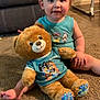 toddler, child, teddy_bear, plush_toy, carpet, living_room, blue_shirt, smiling, sitting, furniture, home_interior, cute, indoor, person, floor, toy, young_child, happy, cozy, casual