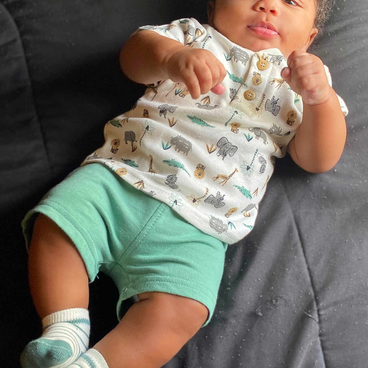 Quadarius is registered to the contest to win money with this photo: animal_print, baby, bed, child, clothing, curly_hair, eyes, face, footwear, hands, indoors, infant, legs, portrait, quilt, relaxing, shirt, shorts, skin, socks