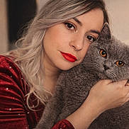 Loky a rejoint le concours — aidez-le/la à gagner de superbes lots ! woman, cat, portrait, close_up, indoor, red_lipstick, gray_cat, amber_eyes, silver_hair, hugging, cozy, calm, intimate, face, pet, feline, cute, warm, soft_texture, casual_clothing