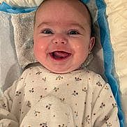 Lou-Anne a rejoint le concours — aidez-le/la à gagner de superbes lots ! baby, smiling, blanket, floral_pattern, pillow, cozy, cute, infant, happy, lying_down, soft, comfort, child, face, indoors, toddler, sleeping_area, warm, clothing, person