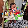 Michael joined the competition — help win amazing prizes! baby, child, indoor, baby_jumper, toy, socks, blanket, wooden_wall, door, curly_hair, floor, playful, colorful, infant, chewing, person, furniture, home, cute, expression