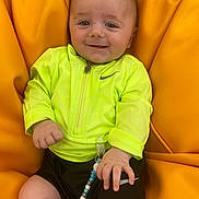 Luca joined the competition — help win amazing prizes! baby, child, neon_jacket, black_shorts, beanbag, orange_background, pacifier_clip, beads, smiling, happy, face, hand, infant, clothing, indoor, person, cute, casual_wear, relaxed, sitting