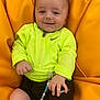 baby, child, neon_jacket, black_shorts, beanbag, orange_background, pacifier_clip, beads, smiling, happy, face, hand, infant, clothing, indoor, person, cute, casual_wear, relaxed, sitting