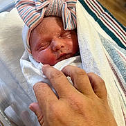 Lyric is registered to the contest to win money with this photo: newborn, baby, sleeping, blanket, hand, hospital, bow, hat, striped, skin, closeup, infant, person, wrapped, cute, tenderness, peaceful, rest, soft, warm