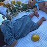 baby, infant, sleeping, blanket, teddy_bear, lemons, lemonade, juice, picnic, outdoor, grass, flowers, floral, blue_blanket, dress, socks, feet, lying_down, still_life, cozy