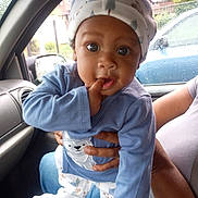 Aha'Mirrion Carroway is registered to the contest to win money with this photo: baby, child, infant, pajamas, hat, car_interior, raindrops, window, person, hand, blue_clothing, cute, curious, indoors, seated, portrait, face, expression, holding, casual