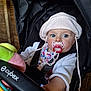 baby, stroller, pacifier, hat, blue_eyes, infant, child, clothing, seatbelt, toy, hand, colorful, pink, white, indoor, closeup, person, cute, face, young