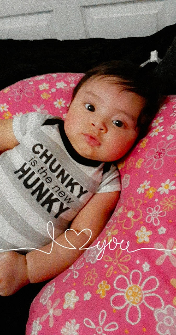 Javon is registered to the contest to win money with this photo: baby, baby_toddler_clothing, cheek, child, comfort, cool, eyelash, happy, linens, lip, magenta, mouth, neck, pattern, person, pink, skin, sleeve, t_shirt, textile