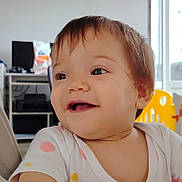 Léa participe au concours pour gagner de l'argent avec cette photo : toddler, child, baby, smiling, happy, indoor, polka_dot, shirt, hand, face, head, furniture, table, chair, window, light, yellow, childproofing, home, curly_hair