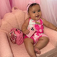 Harlem is registered to the contest to win money with this photo: baby, pink, chair, handbag, phone, headband, jewelry, smile, happy, infant, portrait, couch, fashion, accessory, furniture, child, indoors, cute, plush, person