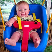 Braxton is registered to the contest to win money with this photo: baby, child, swing, playground, outdoor, smiling, happy, blue_swing, yellow_straps, red_t_bar, grass, trees, wooden_fence, sunlight, cute, infant, person, seat, summer, daylight