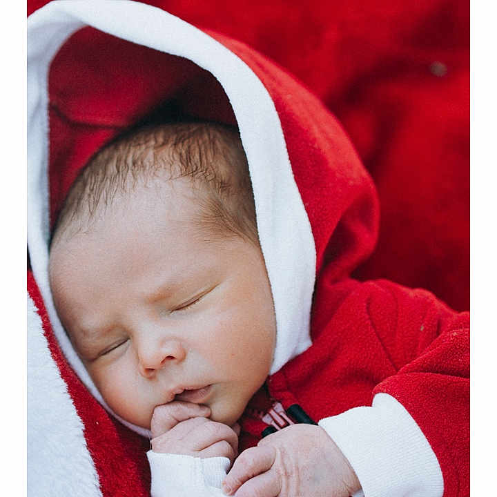 Finley joined the competition — help win amazing prizes! baby, blanket, child, closeup, clothing, cozy, cute, face, hand, indoors, infant, newborn, peaceful, portrait, red_hoodie, resting, sleeping, soft_texture, warm, young
