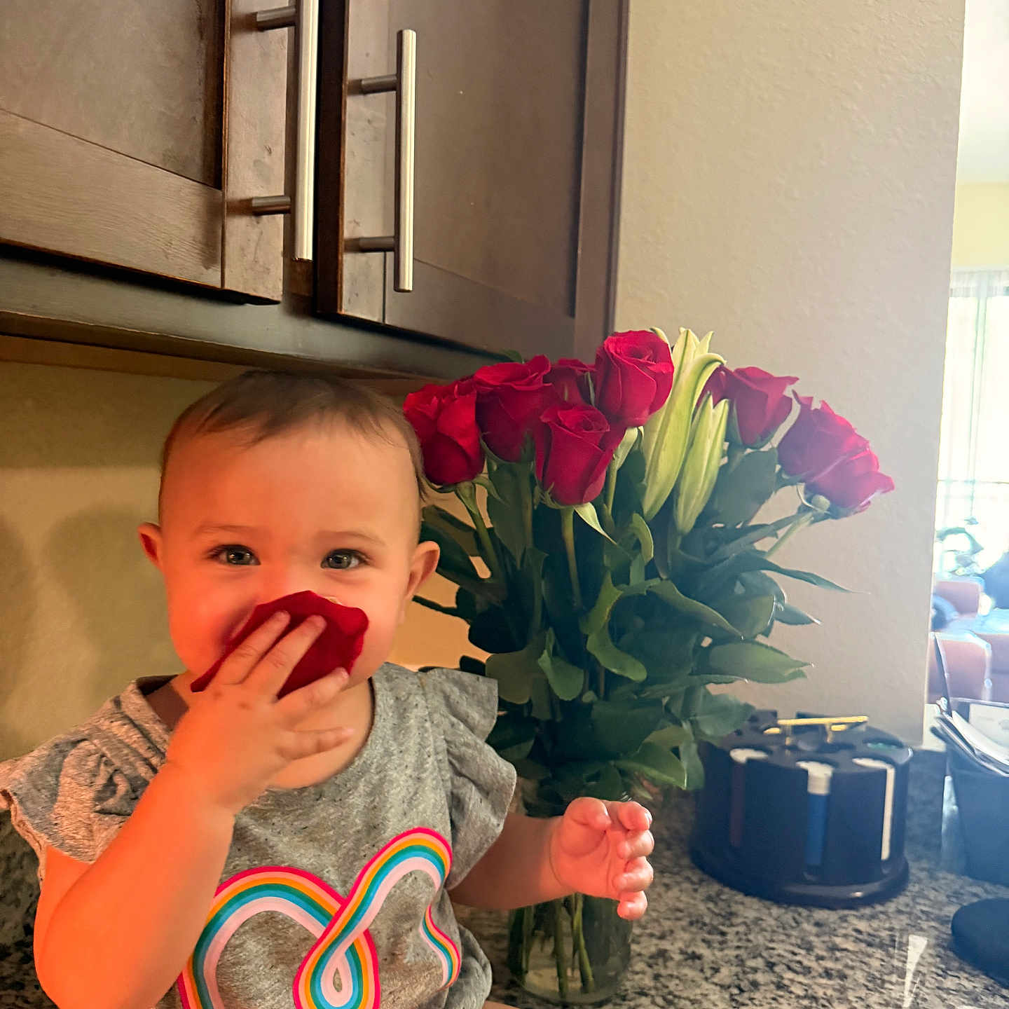 Averie is registered to the contest to win money with this photo: toddler, child, rose_petal, flower, bouquet, kitchen, countertop, cabinet, smile, happy, sitting, indoor, person, shirt, colorful, heart_design, plant, greenery, playful, portrait