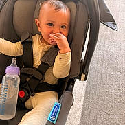 Averie is registered to the contest to win money with this photo: baby, child, car_seat, pacifier, baby_bottle, infant, seatbelt, clothing, cute, sitting, indoor, safety, comfort, person, face, hand, expression, young, toddlers, soft_lighting