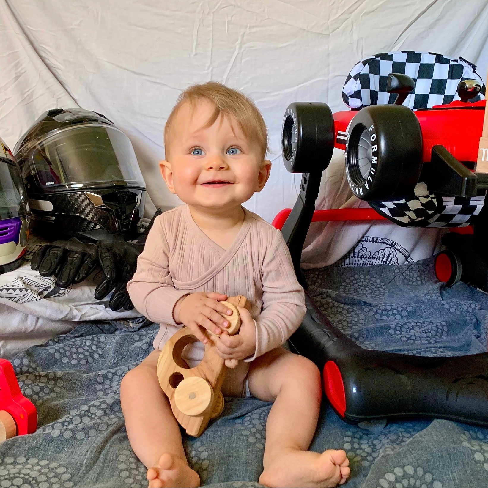 Caleb participe au concours pour gagner de l'argent avec cette photo : baby, blanket, blue_eyes, checkered_flag, child, cute, happy, indoors, infant, milestone, motorcycle_gloves, motorcycle_helmet, playtime, portrait, red_toy_car, sitting, smiling, toy_car, wooden_blocks, wooden_toy