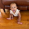baby, barefoot, bracelet, candid, child, floral_outfit, front_view, furniture, happy, hardwood_floor, home, indoors, infant, laughing, leather_sofa, portrait, short_hair, sitting, smiling, toddler