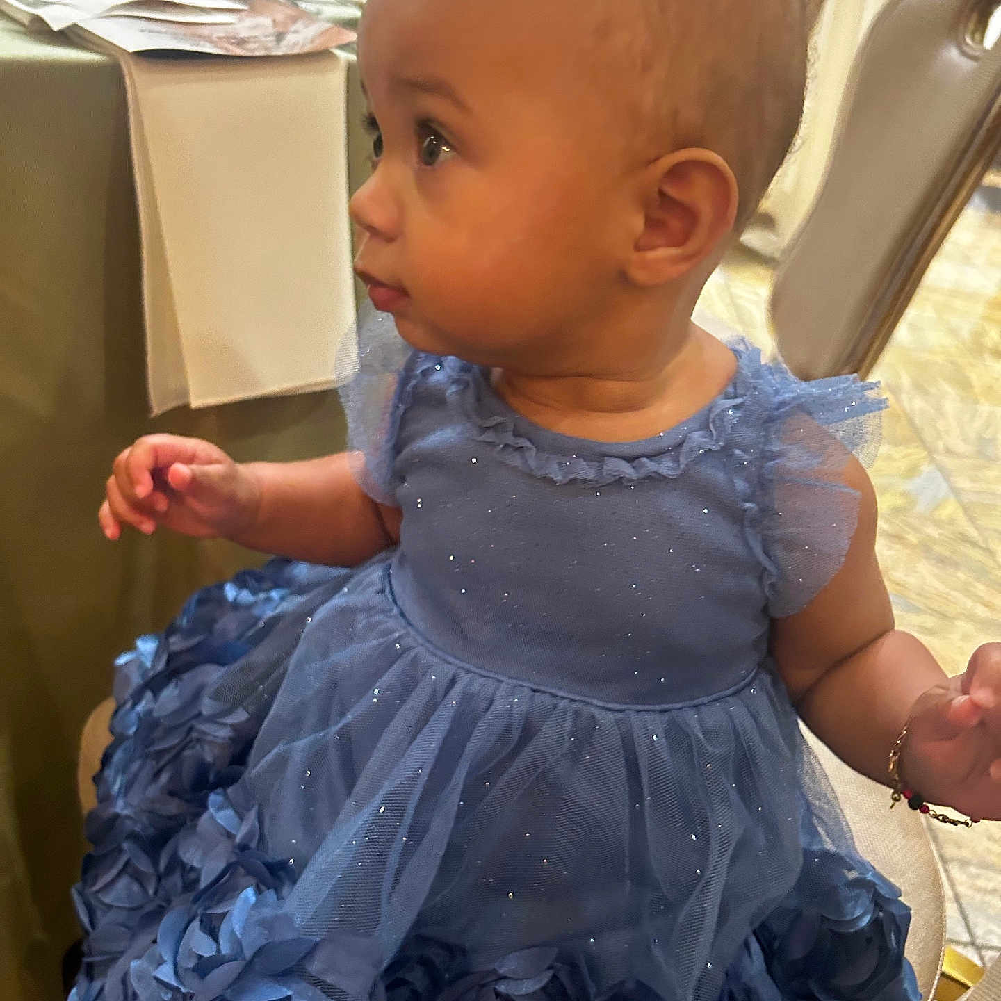 Jai-Lyanna is registered to the contest to win money with this photo: baby, blue_dress, bracelet, chair, child, cute, dining_table, eyes, face, fashion, formalwear, hand, indoor, portrait, restaurant, ruffled_dress, side_profile, sitting, sparkly, toddler