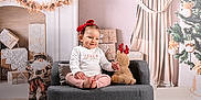 Eloa participe au concours pour gagner de l'argent avec cette photo : child, christmas_tree, cozy, curtains, cute, festive, fireplace, holiday_decorations, indoors, pine_cones, plush_toy, portrait, red_bow, sitting, small_couch, smiling, toddler, white_rug, winter, wrapped_gifts