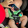 baby, child, car_seat, sunglasses, toy, hand, seatbelt, infant, colorful, playful, closeup, person, casual, cute, indoor, wearing, holding, legs, clothing, seat