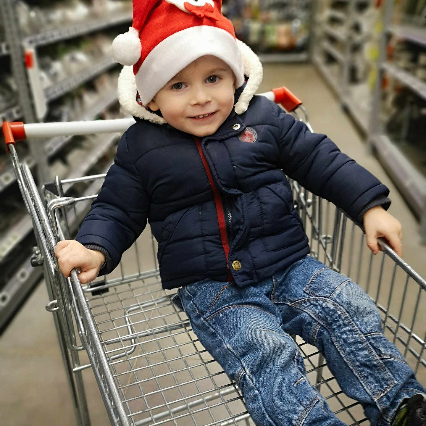 Benjamin participe au concours pour gagner de l'argent avec cette photo : aisle, boy, casual, child, cute, footwear, happy, holiday, indoor, jacket, jeans, metal, person, retail, santa_hat, shopping, shopping_cart, smile, store, winter_clothing