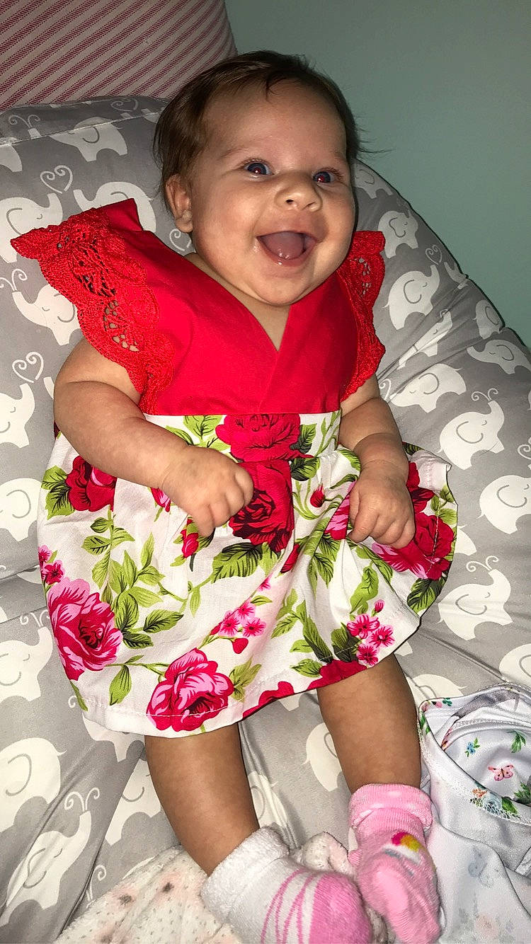 Ava is registered to the contest to win money with this photo: baby, baby_products, baby_toddler_clothing, cheek, child, dress, flower, happy, leg, person, pink, plant, skin, smile, textile, thigh, toddler