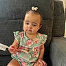 arm, baby, brush, casual, child, clothing, couch, cute, expression, face, floral_pattern, furniture, hair_clip, home, indoor, leg, person, sitting, skin, toddler