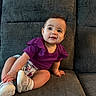 baby, child, couch, cute, furniture, gray_couch, happy, home, indoor, infant, person, playful, portrait, purple_clothing, seated, shorts, smiling, socks, white_shoes, young_child