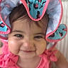Ariella is registered to the contest to win money with this photo: baby, cheerful, child, closeup, cute, expression, face, fashion, happy, hat, headwear, indoors, infant, person, pink_clothing, portrait, ruffle, skin, smile, young_child