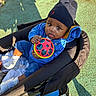 Ayden participe au concours pour gagner de l'argent avec cette photo : baby, child, stroller, toy, ball, blue_outfit, hat, beanie, sneakers, sunlight, outdoor, green_floor, curious, seated, infant, portrait, warm_light, playful, person, casual_clothing