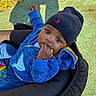 Ayden participe au concours pour gagner de l'argent avec cette photo : baby, child, stroller, blue_jacket, beanie, fingers_in_mouth, outdoor, sunlight, shadow, curious, face, portrait, person, casual_clothing, infant, playground_surface, seat, headwear, young_child, cozy