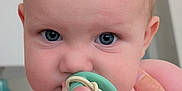 Mia joined the competition — help win amazing prizes! baby, infant, pacifier, hand, blue_eyes, close_up, skin, cute, child, person, portrait, indoor, holding, fingers, face, expression, young, human, newborn, support