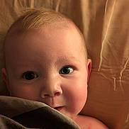 Mia joined the competition — help win amazing prizes! baby, blanket, face, skin, eyes, infant, closeup, expression, cute, child, portrait, soft_lighting, indoors, young, head, person, sleeping_area, cozy, resting, curious
