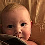 baby, blanket, face, skin, eyes, infant, closeup, expression, cute, child, portrait, soft_lighting, indoors, young, head, person, sleeping_area, cozy, resting, curious