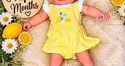 Kailani joined the competition — help win amazing prizes! baby, infant, yellow_dress, headband, smiling, fluffy_rug, lemons, flowers, wooden_sign, milestone, cute, lying_down, white_socks, happy, portrait, fresh_fruit, decor, celebration, child, four_months