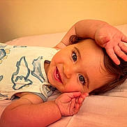 Tommy joined the competition — help win amazing prizes! baby, smiling, infant, lying_down, white_outfit, animal_print, blue, pink_background, cute, happy, child, portrait, face, hands, skin, hair, eyes, teeth, playful, person
