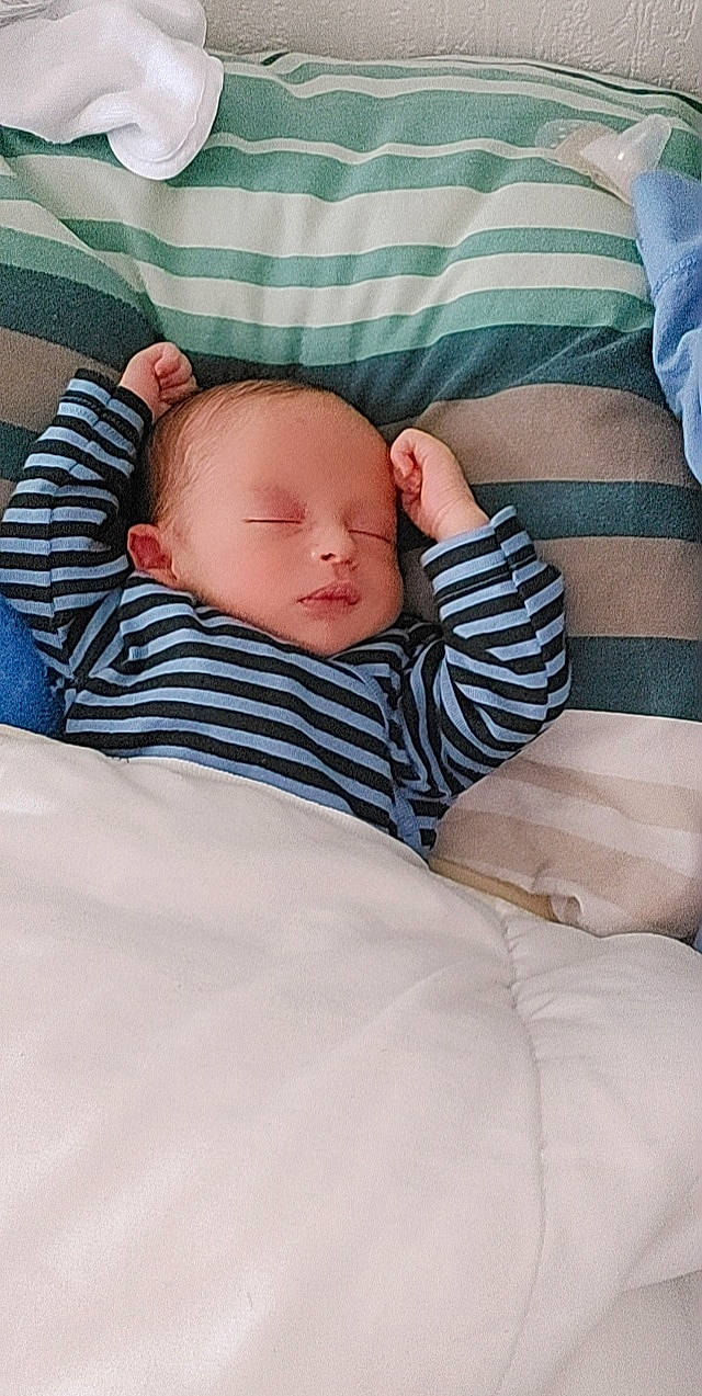 Ismail participe au concours pour gagner de l'argent avec cette photo : baby, baby_sleeping, baby_toddler_clothing, bedding, cheek, child, collar, comfort, human_body, linens, pattern, person, portrait_photography, room, sitting, skin, sleeve, t_shirt, toddler