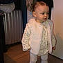 Inaya participe au concours pour gagner de l'argent avec cette photo : toddler, child, indoor, clothing, vest, boots, leggings, floor, curly_hair, standing, looking_away, winter_wear, brown_boots, white_vest, patterned_shirt, wooden_floor, suitcase, hanger, warm_clothing, person