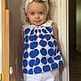 Inaya a rejoint le concours — aidez-le/la à gagner de superbes lots ! toddler, child, girl, headband, bow, polka_dot, shirt, white_pants, standing, indoor, wall, doorframe, wooden_furniture, curly_hair, smiling, portrait, casual_clothing, playful, young_child, cute