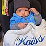 Kaïs a rejoint le concours — aidez-le/la à gagner de superbes lots ! baby, blanket, blue_clothing, car_safety, car_seat, child, cozy, cute, embroidered_text, expression, gray_hat, hat, indoor, infant, jacket, person, portrait, seated, warm_clothing, young_child