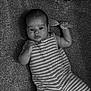 baby, black_and_white, carpet, casual, child, cozy, cute, face, hairbrush, home, indoor, infant, lying_down, monochrome, person, portrait, relaxed, small_hand, striped_clothing, young